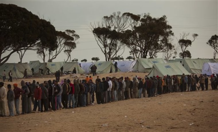 Men, who used to work in Libya but recently fled the unrest, line up as they wait for food in a refugee camp at the Tunisia-Libyan border, in Ras Ajdir, Tunisia, on Tuesday. A Red Crescent official says soldiers loyal to Libyan strongman Moammar Gadhafi are blocking some 30,000 migrant workers from fleeing into Tunisia and forcing many to return to work in the Libyan capital.